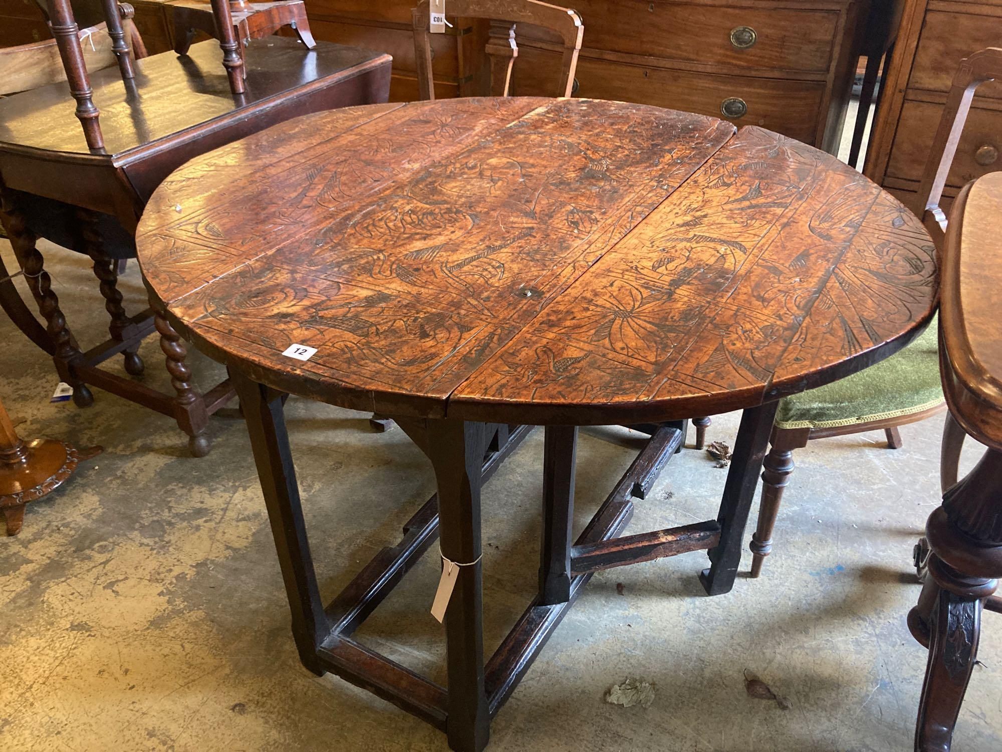 An 18th century carved and stained walnut gateleg table, with oak underframe, width 106cm, 116cm with flaps out, height 74cm